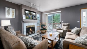 A living room with a fireplace, a sofa set, a coffee table, and a view of the outdoors. - Blue Granite Off Main Townhome: Updated, Great Location (Frisco)
