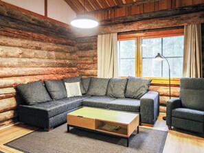 A log cabin interior with a sectional sofa, a small coffee table, and a single armchair.