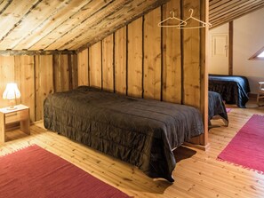 Un lit simple dans une pièce aux murs en bois et au plafond en pente.