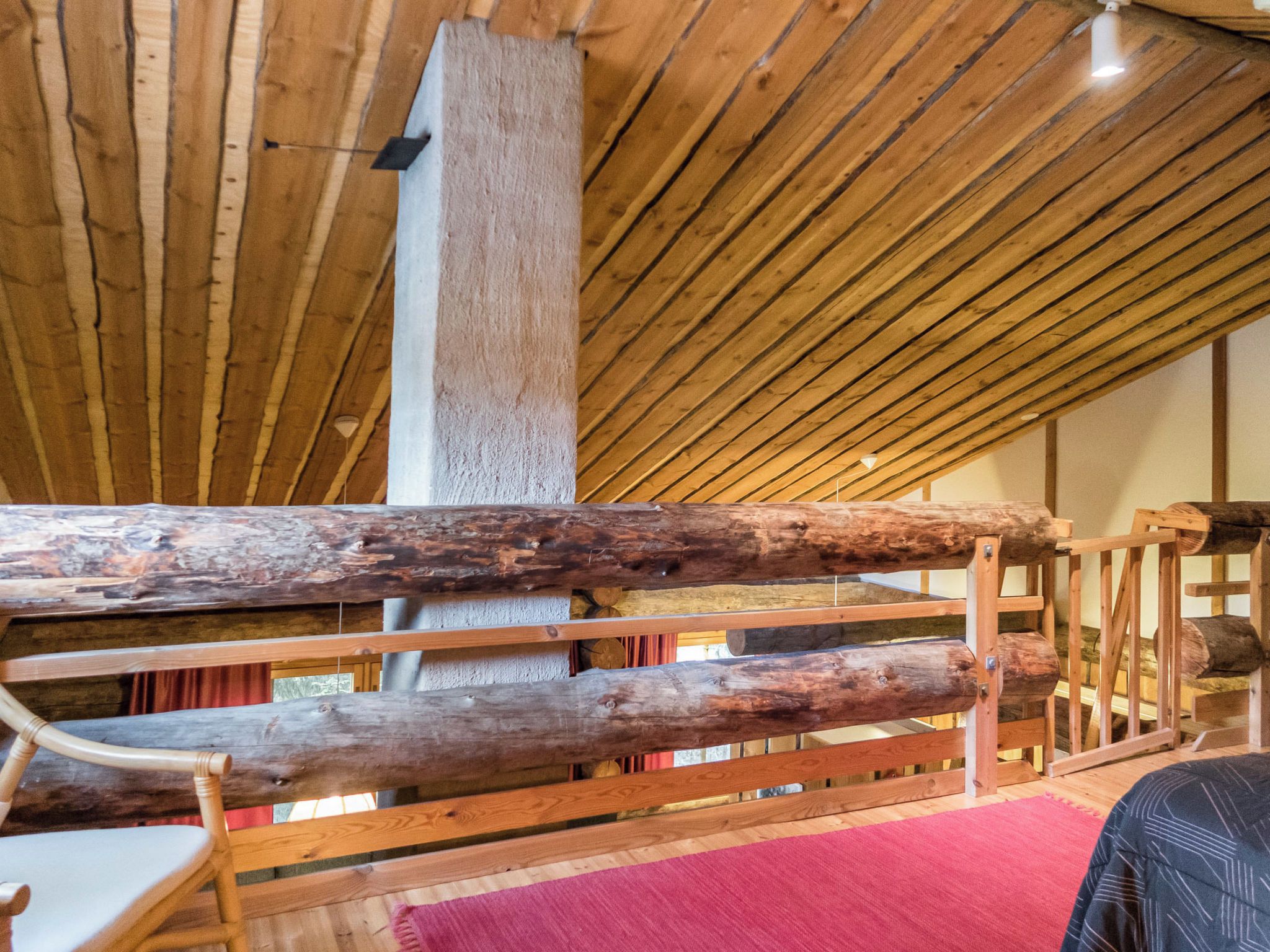 Un intérieur en bois avec un plafond en pente et une structure centrale en poutres de bois.