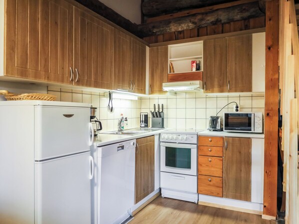 A kitchen with wooden cabinets, a white refrigerator, a stove, and a microwave.