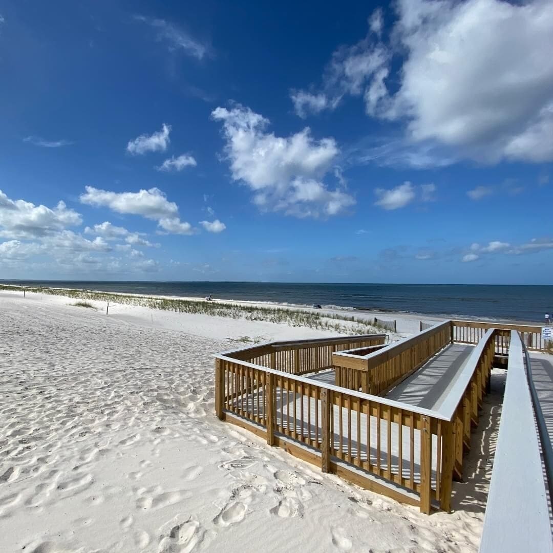 A beach with a wooden boardwalk leading to the ocean.