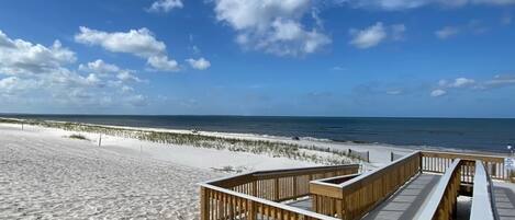 A beach with a wooden boardwalk leading to the ocean.
