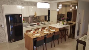 Een moderne keuken met een eethoek, roestvrijstalen apparatuur en een centraal kookeiland met zitplaatsen.