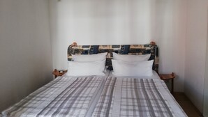 A bed with a patterned headboard, two pillows, and a bedside table with a lamp. - We invite you to our apartment (Bezirk Charlottenburg-Wilmersdorf)