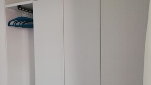 A white wardrobe with multiple compartments and a blue hanger on the top shelf. - We invite you to our apartment (Bezirk Charlottenburg-Wilmersdorf)