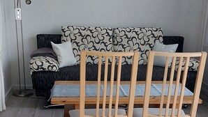 A room with a wooden dining table and chairs, a sofa with patterned cushions, and a floor lamp. - We invite you to our apartment (Bezirk Charlottenburg-Wilmersdorf)