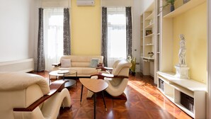 Un salon avec un canapé, des fauteuils, une table basse et une statue posée sur une étagère.