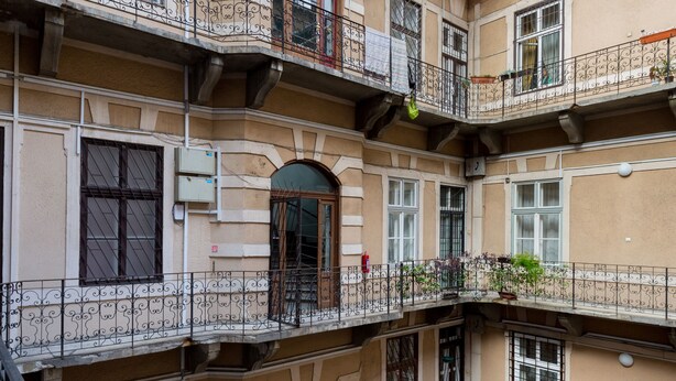 Un immeuble à plusieurs étages doté de balcons, de fenêtres en arc de cercle et d’un sol carrelé.