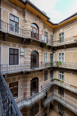 Un edificio de varios pisos con balcones, ventanas de arco y suelo de baldosas.