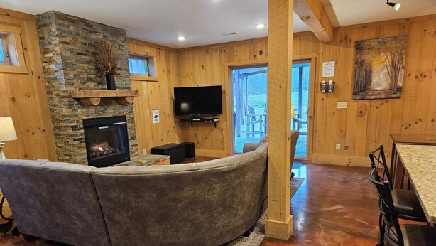A cozy living room with a stone fireplace, a flat-screen TV, and a curved sofa. - Hidden Valley - modern, rustic, unique (Rockbridge)