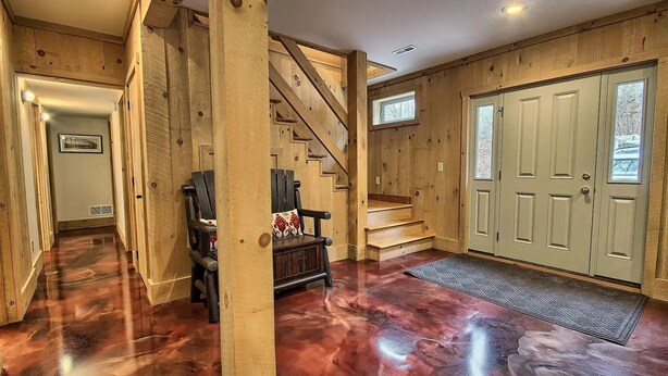 Interior de madera con una escalera, un banco y una puerta.