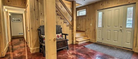 A wooden interior with a staircase, a bench, and a door.