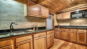 A kitchen with wooden cabinets, a granite countertop, and a black microwave. - Hidden Valley - modern, rustic, unique (Rockbridge)
