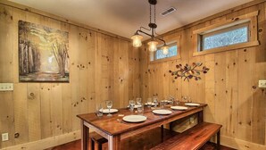 A wooden dining area with a long table set for four, a bench, and a painting on the wall. - Hidden Valley - modern, rustic, unique (Rockbridge)