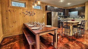 Una cocina con paneles de madera, una isla central, horno empotrado y un refrigerador de acero inoxidable.