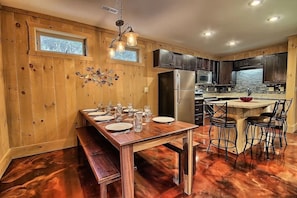 Una cocina con paneles de madera, una isla central, horno empotrado y un refrigerador de acero inoxidable.
