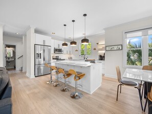 A modern kitchen with a central island, stainless steel appliances, and pendant lighting.