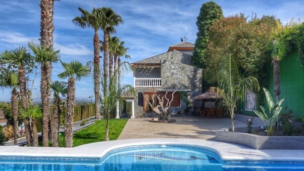A swimming pool with a stone house in the background, surrounded by palm trees. - El Balcon by Interhome (Córdoba/Baena)