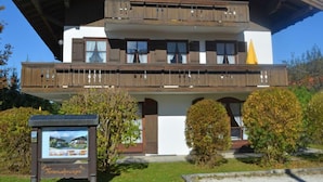 Un bâtiment à deux étages avec une façade en bois, des balcons surmontés d’auvents jaunes et une enseigne devant l’entrée.