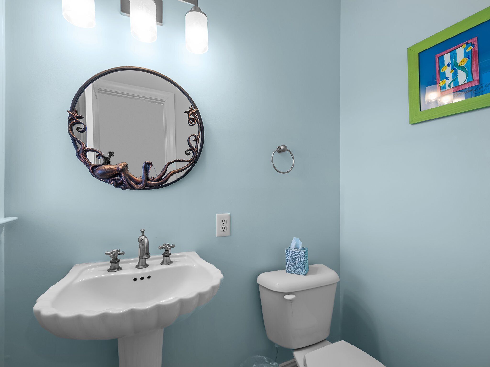 A bathroom with a white sink, a round mirror, and a toilet.