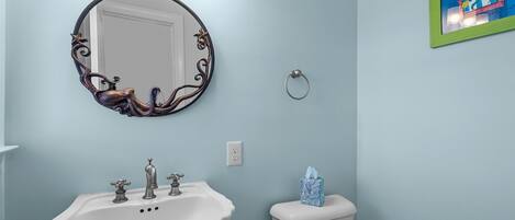 A bathroom with a white sink, a round mirror, and a toilet.