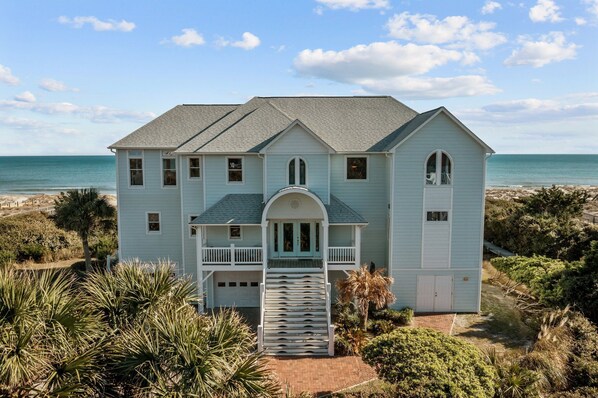 A light blue house with a front porch, a garage, and a view of the ocean. - Oceanfront,private pool,elevator,views galore!Located in Spinnakers Reach (Emerald Isle)