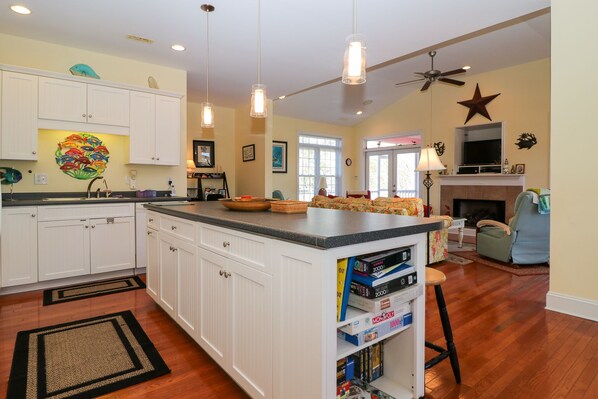 A spacious kitchen with white cabinets, a large island, and a dining area with a fireplace.