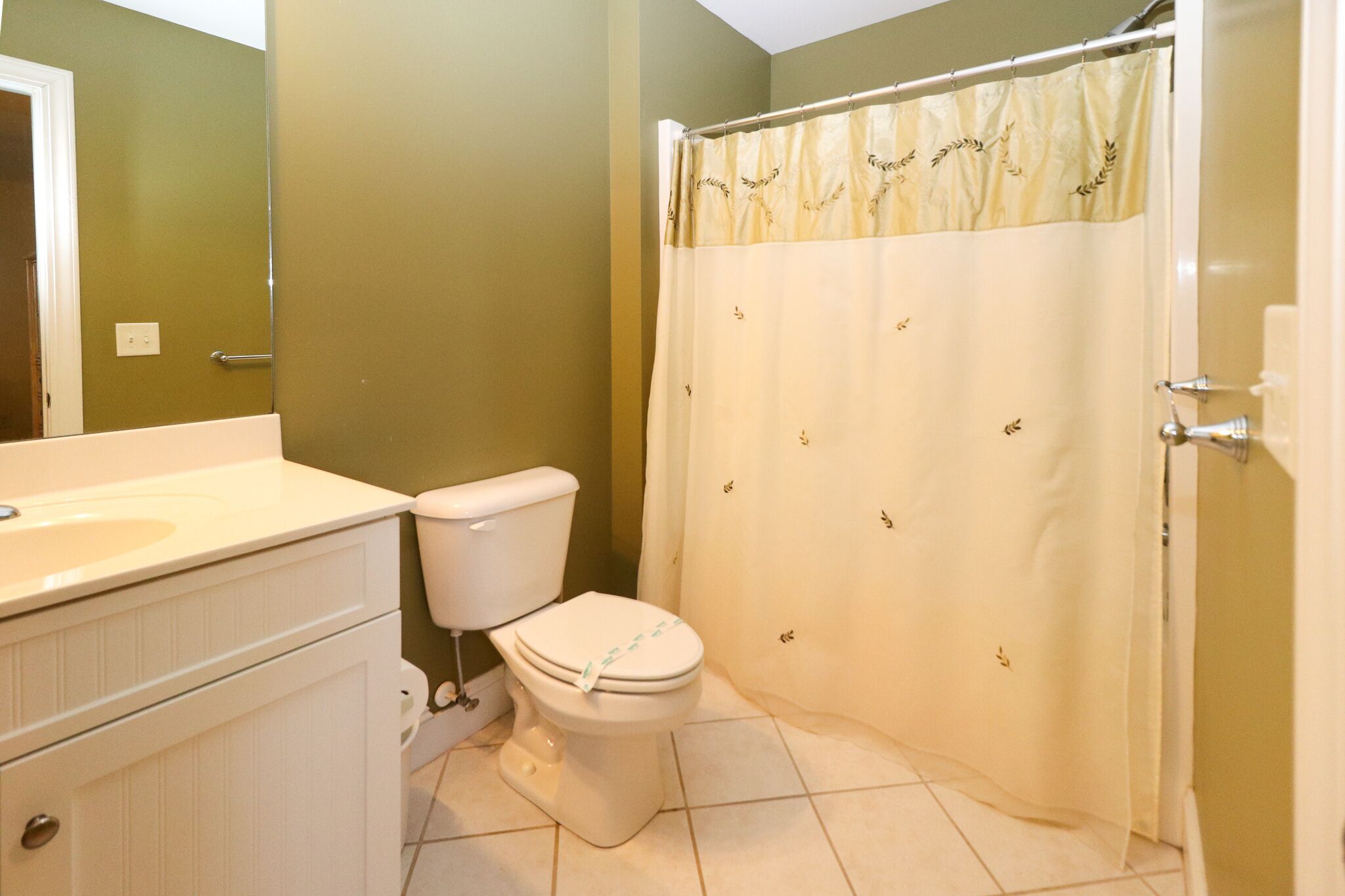A bathroom with a toilet, sink, and shower curtain.
