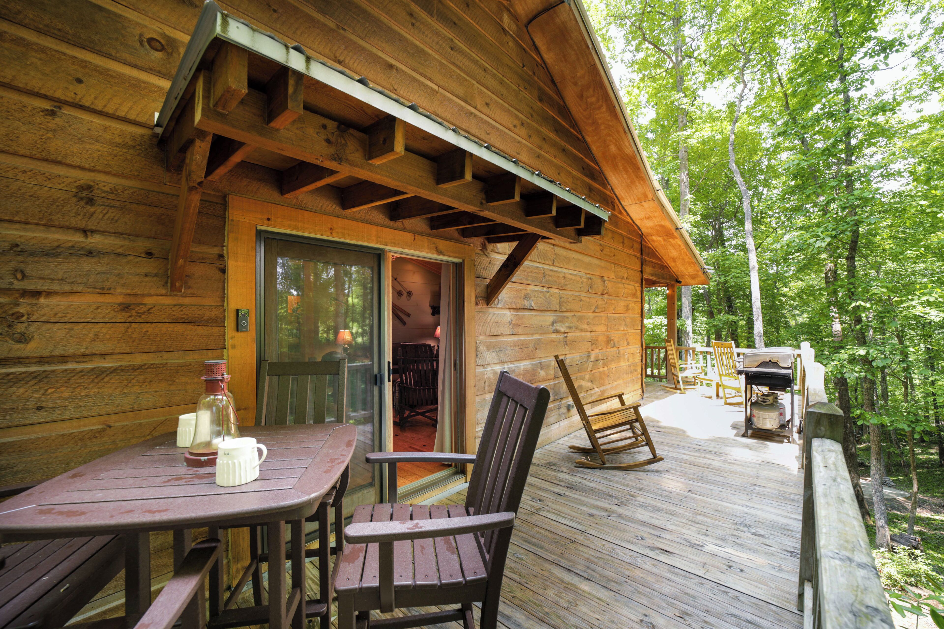 Une cabane en bois avec une terrasse, une table et des chaises, et un fauteuil à bascule.