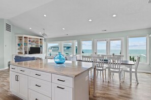 A spacious living area with a large island, white cabinetry, and a view of the ocean. - Emerald Dream: Sun, Sand & Splash Zone (Emerald Isle)