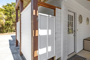 A white building with a wooden porch, a door, and a small window.