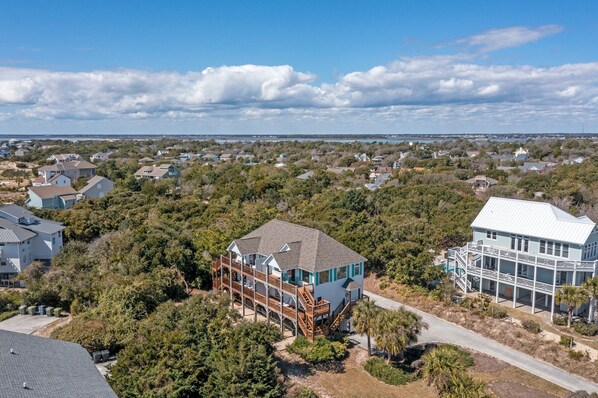 A coastal residential area with a prominent house featuring a large deck and a second-story balcony.