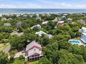 Vista aérea de un área residencial con casas, una piscina y vistas al océano.