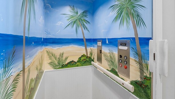 Una stanza con un murale raffigurante una spiaggia, palme e un pannello di controllo.