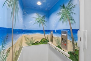 Una habitación con un mural de playa, palmeras y un panel de control.