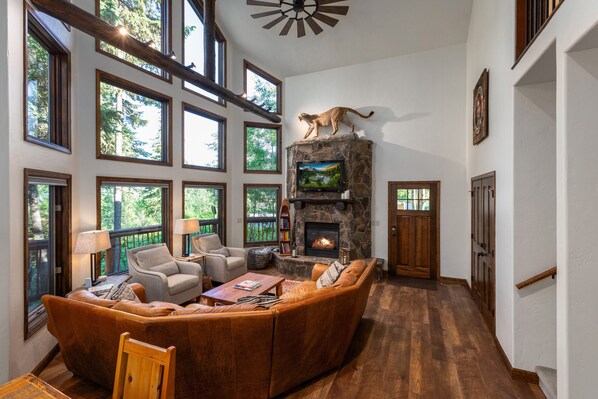 Un salón amplio con chimenea de piedra, ventanas grandes y una zona de estar acogedora.