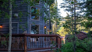 A rustic cabin with a wooden deck, surrounded by dense forest. - Spacious Whitefish Mountain residence with some of the best ski in/out on the mountain. (Whitefish)