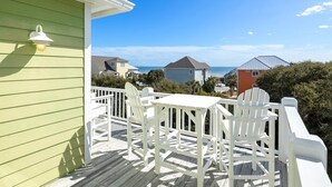 A green building with a white deck, white chairs, and a table. - Oceanview with elevator, private pool, golf cart, in Spinnakers Reach community (Emerald Isle)