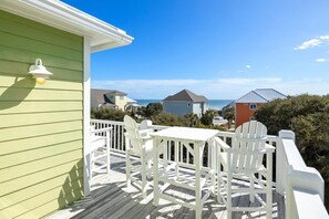 A green building with a white deck, white chairs, and a table.