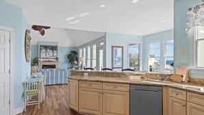 A spacious kitchen with a large island, wooden cabinets, and a view to the outside. - Oceanview with elevator, private pool, golf cart, in Spinnakers Reach community (Emerald Isle)