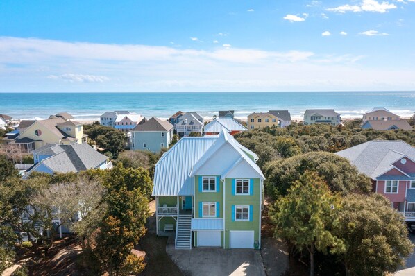 A coastal residential area with houses, a beach, and a clear sky.