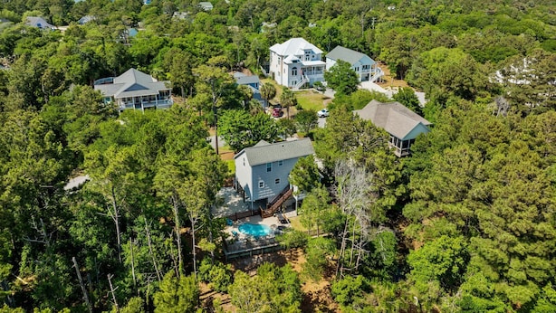 A large, multi-story house surrounded by dense forest, with a visible swimming pool and a dock extending into a body of water. - Pet Friendly, Oceanside Interior Home Private Pool, Golf Cart, and Easy Access. (Emerald Isle)