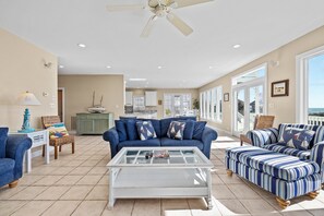A spacious living area with a blue sofa, striped armchair, and a white coffee table. - Oceanfront Oasis with Private Pool, Beach Access & Stunning Views – Perfect for (Emerald Isle)