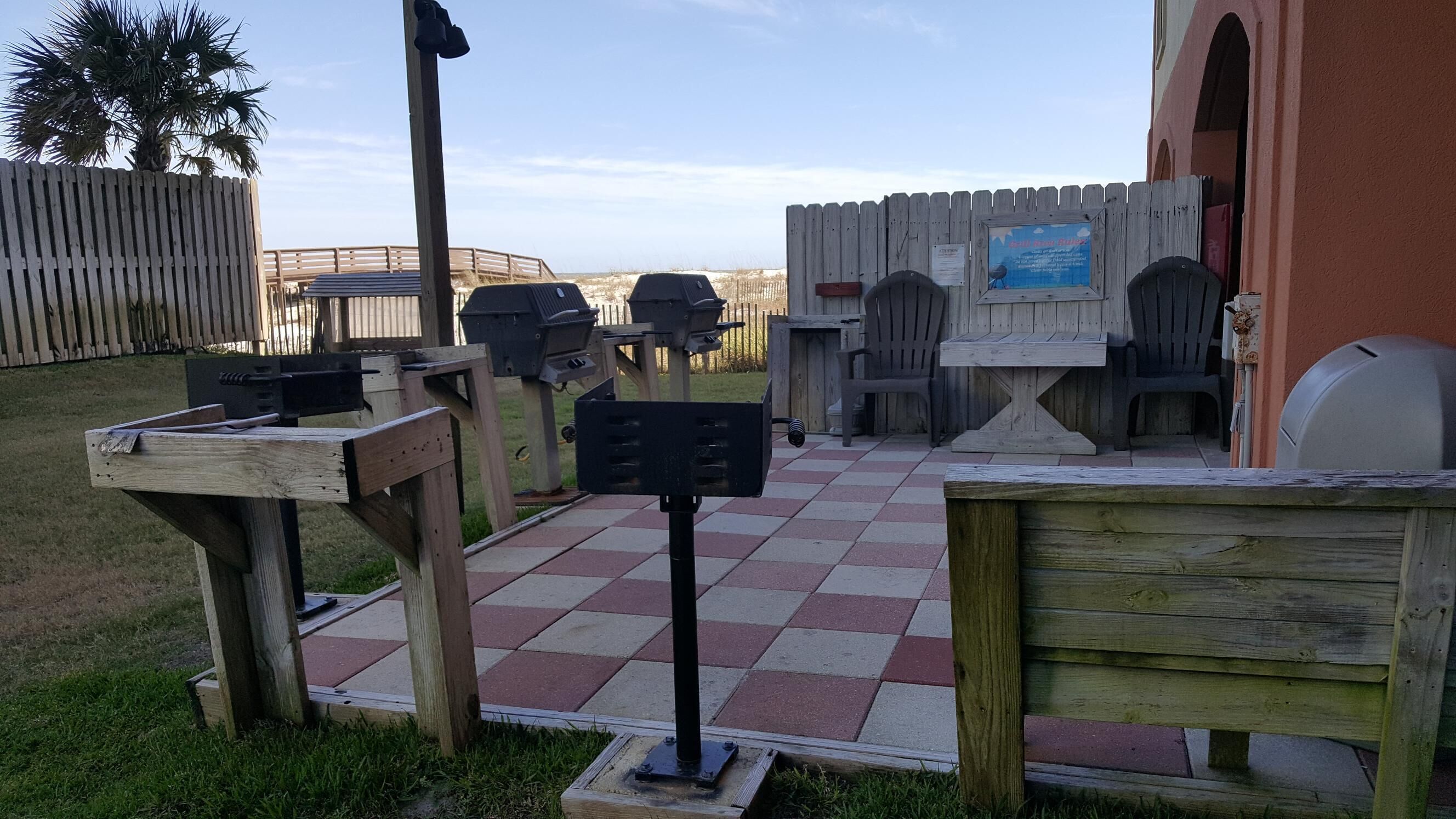 Un espace extérieur aménagé en terrasse, avec un sol carrelé à motifs, des meubles en bois et des barbecues.
