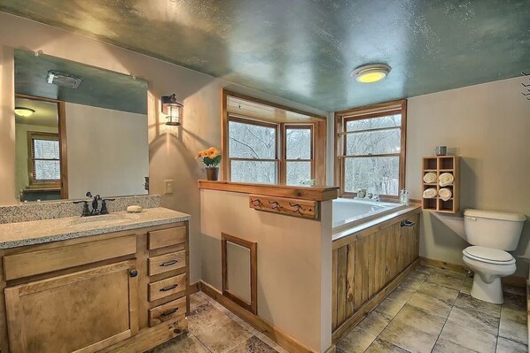 A bathroom with wooden cabinets, a sink, a toilet, and a window. - Two Trees - A Unique Custom Cabin (Rockbridge)