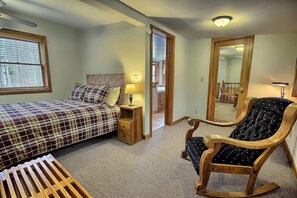 Un dormitorio con cama, mesita de noche, mecedora y espejo.