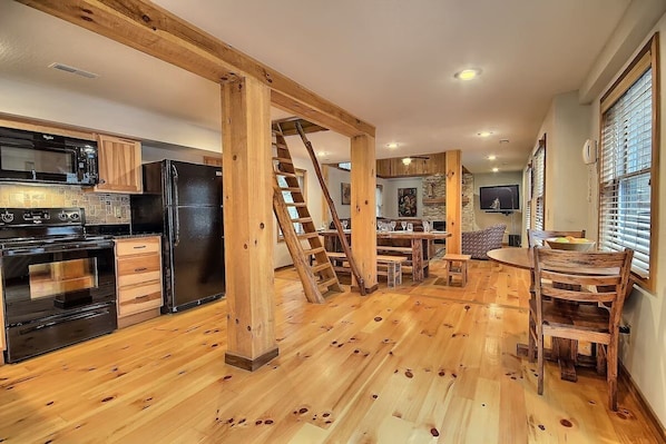 A spacious kitchen with wooden beams, a built-in stove, and a refrigerator.