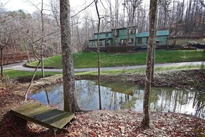 Un chalet au bord du lac, doté d’une terrasse et entouré d’arbres et d’un petit étang.