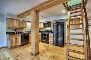 A kitchen with wooden cabinets, a black refrigerator, a microwave, and a dishwasher.